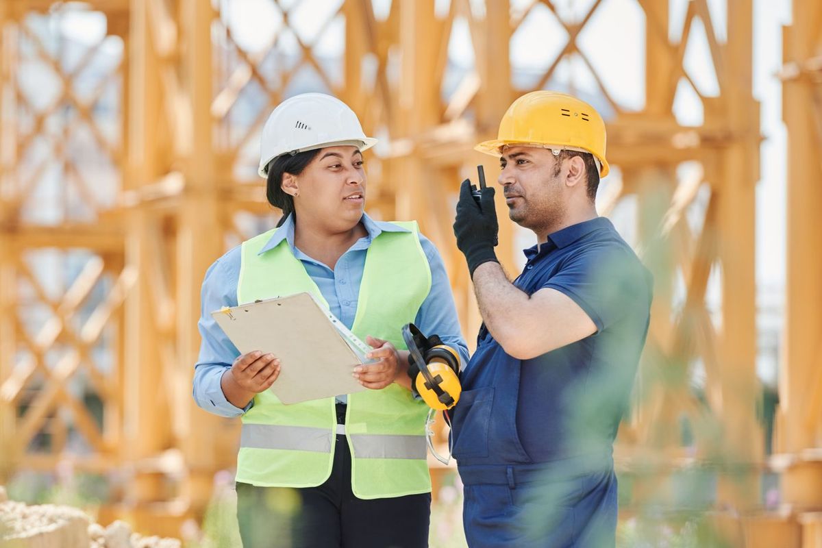 Supervisores con casco y chaleco coordinando en obra